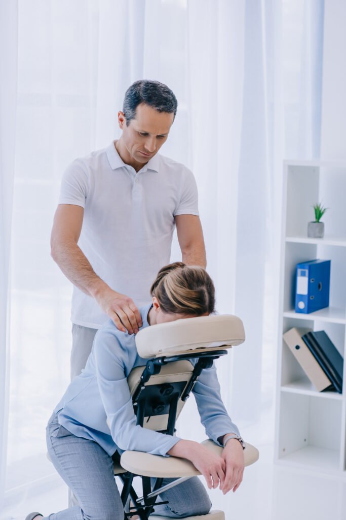 handsome masseur doing seated massage for businesswoman
